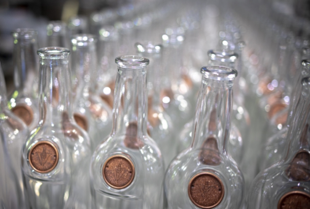 Empty Virginia Distillery bottles lined up and ready for filling on the line, with the iconic magnetic medallion visible. 